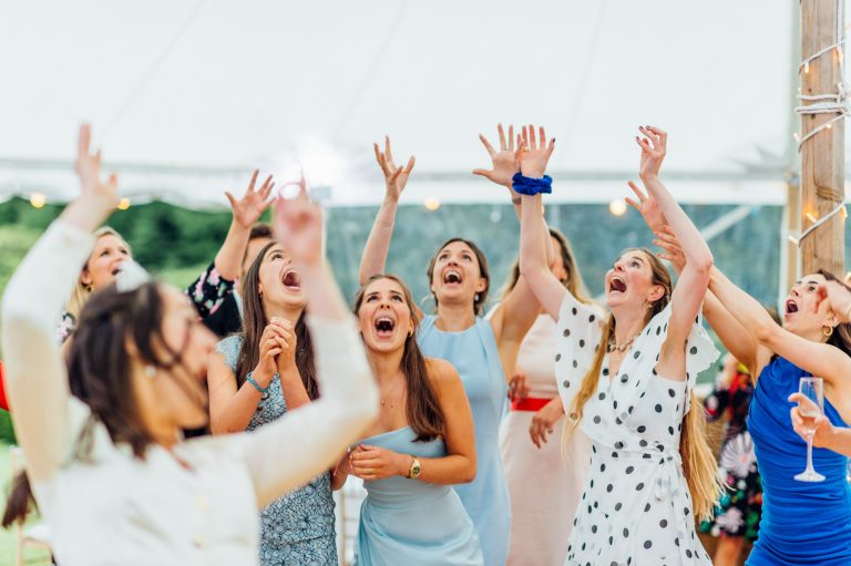 Bridesmaids laughing in the sailcloth tent. bouquet been throw.