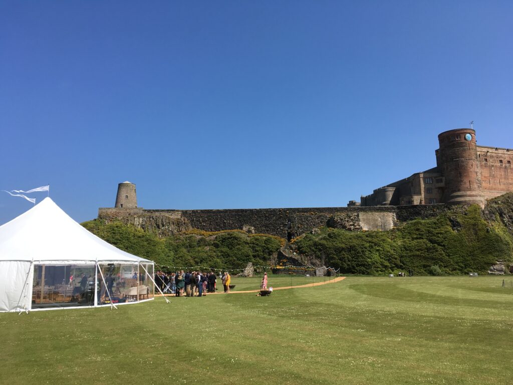Wedding in the grounds of Bamburgh castle in a Sperry style tent.