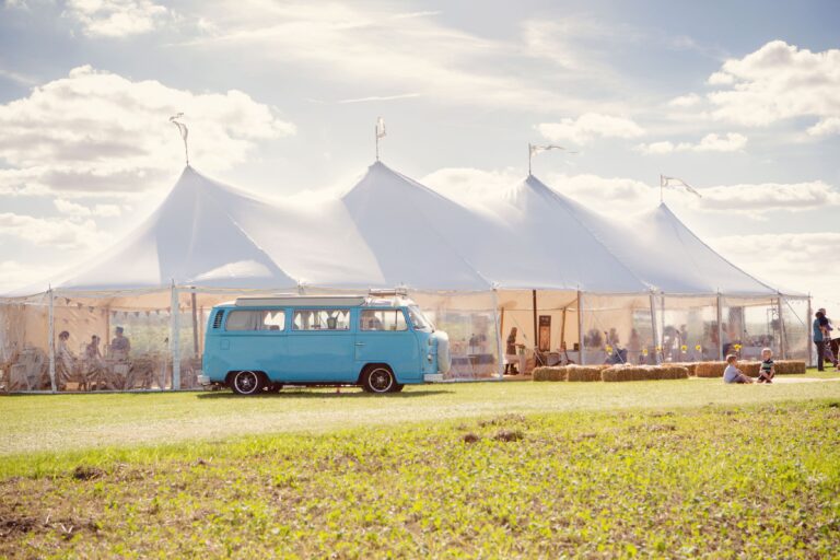 4 pole tent at a festival with a camper van parked outside in the summer