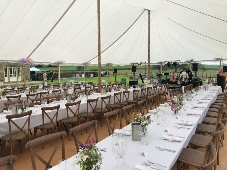 Interior of the sailcloth tent laid up with long tables and chairs for the wedding.