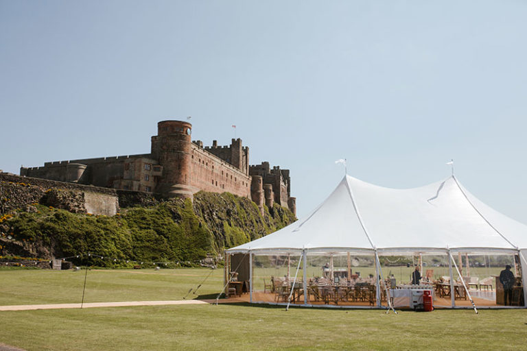Sailcloth marquee with three poles in the tent. Wedding party of 150 guests in the marquee at Bambrugh Castle.